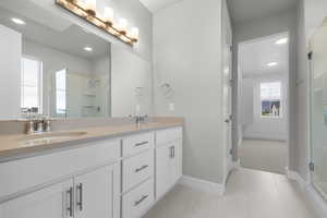 Bathroom featuring a stall shower, double vanity, light tile patterned floors, and recessed lighting