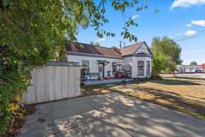 View of east unit with a shed, stucco siding, a shingled roof, a lawn, and a patio area