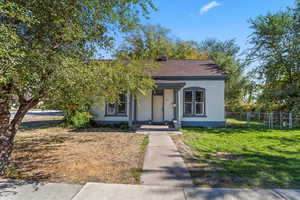 View of front of house with stucco siding, a porch, and shingled roof