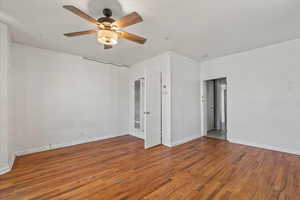 Unfurnished bedroom with wood finished floors, a ceiling fan, and a heating unit