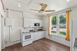 Kitchen featuring white cabinetry, white appliances, dark countertops, dark wood-style floors