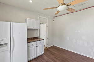 Kitchen featuring white fridge, a ceiling fan, white cabinetry, and dark wood-style floors