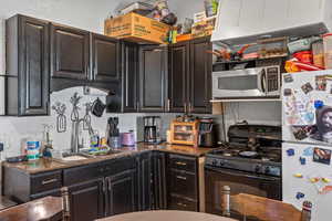 Kitchen with black gas stov, stainless steel microwave, and dark brown cabinets
