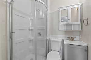 Bathroom with a textured wall, a stall shower, and vanity