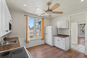 Kitchen with range with electric cooktop, white cabinetry, wood finished floors, and white refrigerator