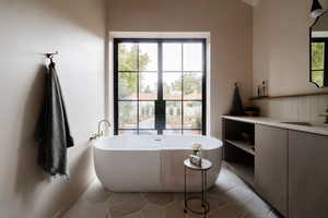 Full bathroom with a freestanding tub, vanity, french doors, and light tile patterned floors