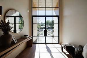 Doorway featuring floor to ceiling windows, wood finished floors, and a towering ceiling