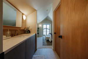 Bathroom featuring lofted ceiling, vanity, and light colored carpet