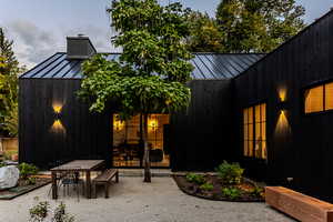 Back of property with a standing seam roof, a metal roof, a chimney, a patio area, and outdoor dining area