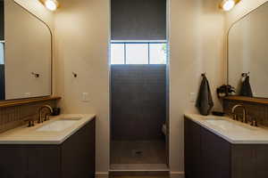 Bathroom featuring decorative backsplash, two vanities, and a tile shower