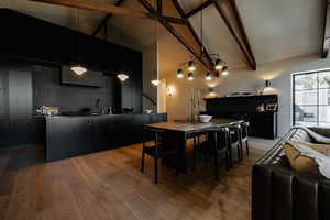 Dining room with beam ceiling, high vaulted ceiling, light wood-type flooring, and a chandelier