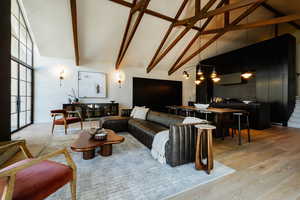 Living room with light wood finished floors, high vaulted ceiling, and beamed ceiling