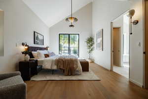 Bedroom featuring high vaulted ceiling and light wood-type flooring