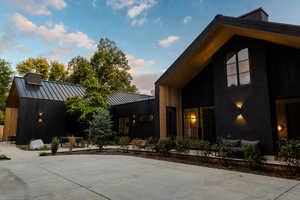 View of side of property with a standing seam roof, a metal roof, a patio, and a chimney