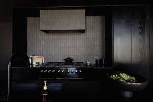 Kitchen featuring dark countertops, ventilation hood, high end black range oven, and dark cabinets