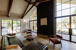 Living room featuring high vaulted ceiling, wood finished floors, beamed ceiling, and a large fireplace