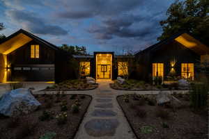 Mid-century modern home with a garage, a standing seam roof, driveway, and a metal roof