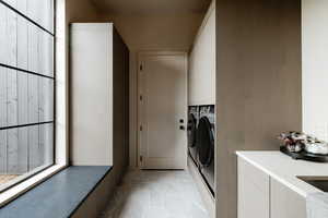 Laundry room featuring light tile patterned floors, washing machine and clothes dryer, and cabinet space