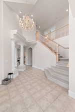Entryway with a high ceiling, recessed lighting, decorative columns, light tile patterned floors, and arched walkways
