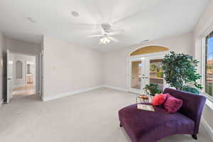 Living area featuring french doors, light colored carpet, a ceiling fan, and arched walkways
