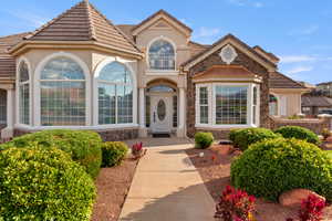 View of exterior entry with stone siding, stucco siding, and a tiled roof