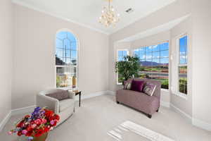 Sitting room with carpet, plenty of natural light, ornamental molding, a chandelier, and a mountain view