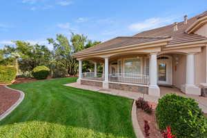 View of grassy yard featuring covered porch