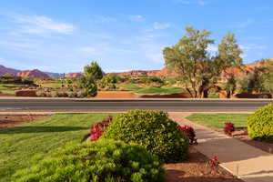 View of community with a mountain view, a lawn, and view of golf course
