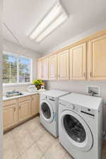 Laundry area with separate washer and dryer, cabinet space, and light tile patterned flooring