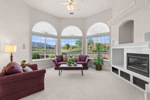 Carpeted living room featuring a tile fireplace, ceiling fan, and a mountain view