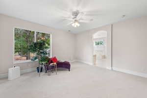 Sitting room with carpet, arched walkways, and ceiling fan