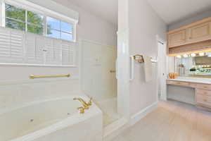 Bathroom with vanity, a marble finish shower, and a jetted tub