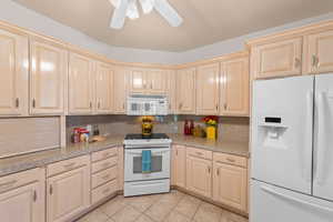 Kitchen featuring white appliances, light brown cabinetry, light tile patterned floors, and tile countertops