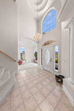 Foyer entrance with stairway, a towering ceiling, light tile patterned flooring, and healthy amount of natural light
