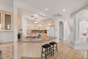 Kitchen featuring arched walkways, light brown cabinets, a peninsula, recessed lighting, and a kitchen breakfast bar