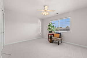 Living area featuring carpet and a ceiling fan