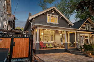 Rear view of property featuring covered porch, a chimney, and a gate