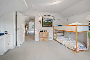 Bedroom featuring lofted ceiling and light carpet