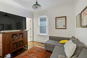 Living room with dark wood finished floors and crown molding