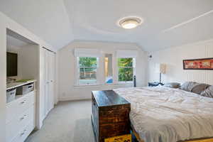 Bedroom with lofted ceiling, light carpet, and a closet