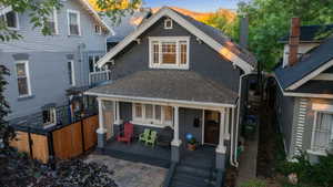 View of front facade featuring a chimney, roof with shingles, and covered porch