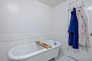 Full bath featuring a decorative wall and a soaking tub