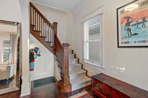 Stairway featuring wood finished floors and crown molding