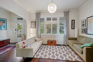 Living room with wood finished floors, ornamental molding, and arched walkways