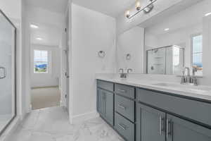 Bathroom featuring a shower stall, double vanity, and light marble finish floors