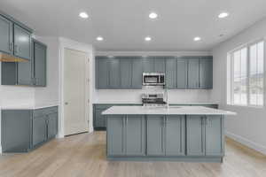 Kitchen featuring light stone countertops, recessed lighting, tasteful backsplash, light wood-style flooring, and stainless steel appliances
