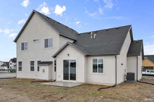 Back of property featuring roof with shingles, a patio area, and stucco siding