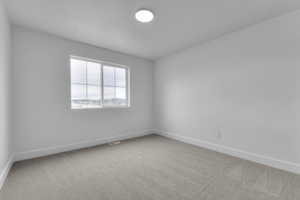 Empty room featuring baseboards and light colored carpet