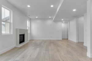 Unfurnished living room featuring recessed lighting, light wood-type flooring, and a glass covered fireplace