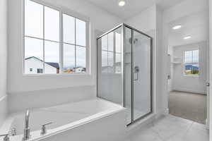 Bathroom featuring a stall shower, light marble finish floors, a garden tub, and recessed lighting